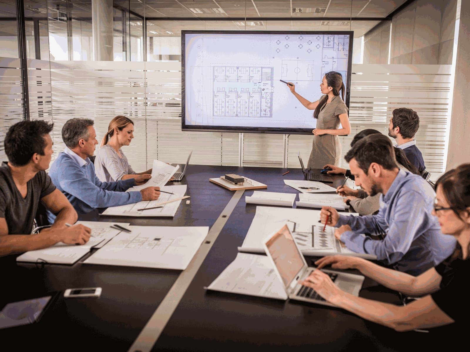 An architect presenting floor plans to a team around a meeting table