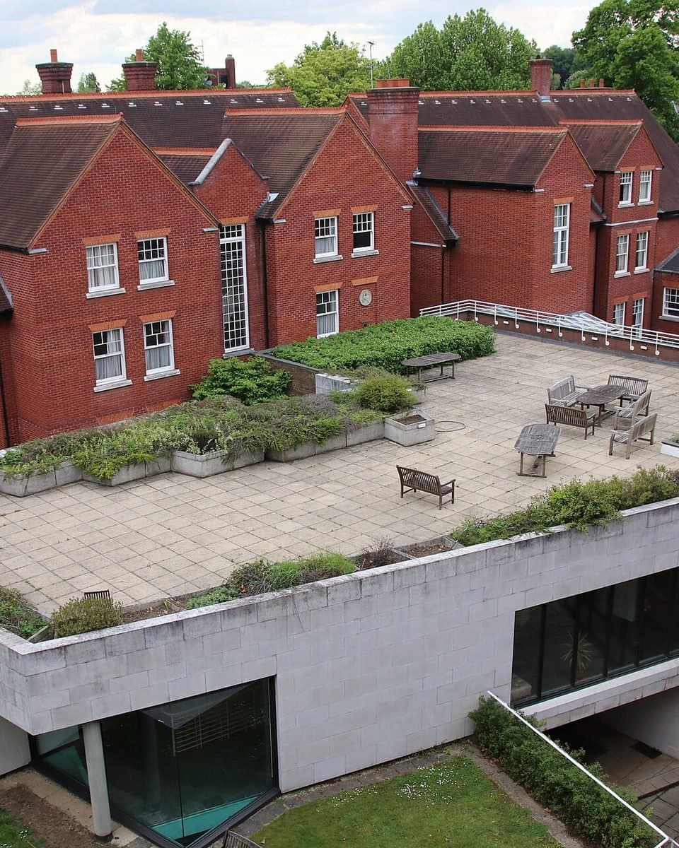 A contemporary building with a green roof among red-brick houses