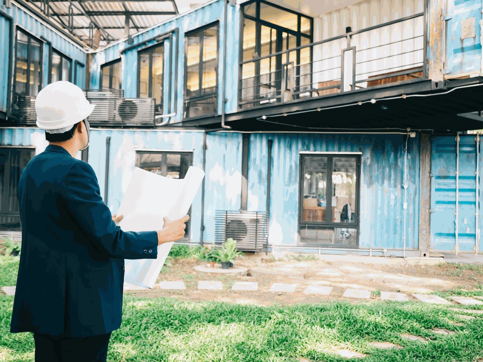 A man in a hard hat holding plans outside a converted building
